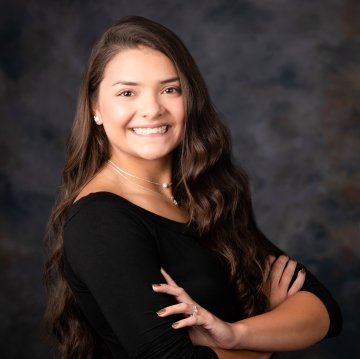 Headshot of Jada Masiclat, with long, dark wavy hair and a simple black long-sleeved shirt.